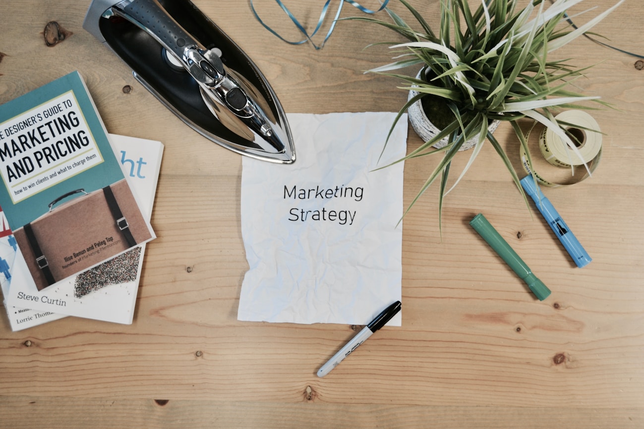 Sổ tay và tờ giấy ghi Marketing Strategy trên mặt bàn gỗ